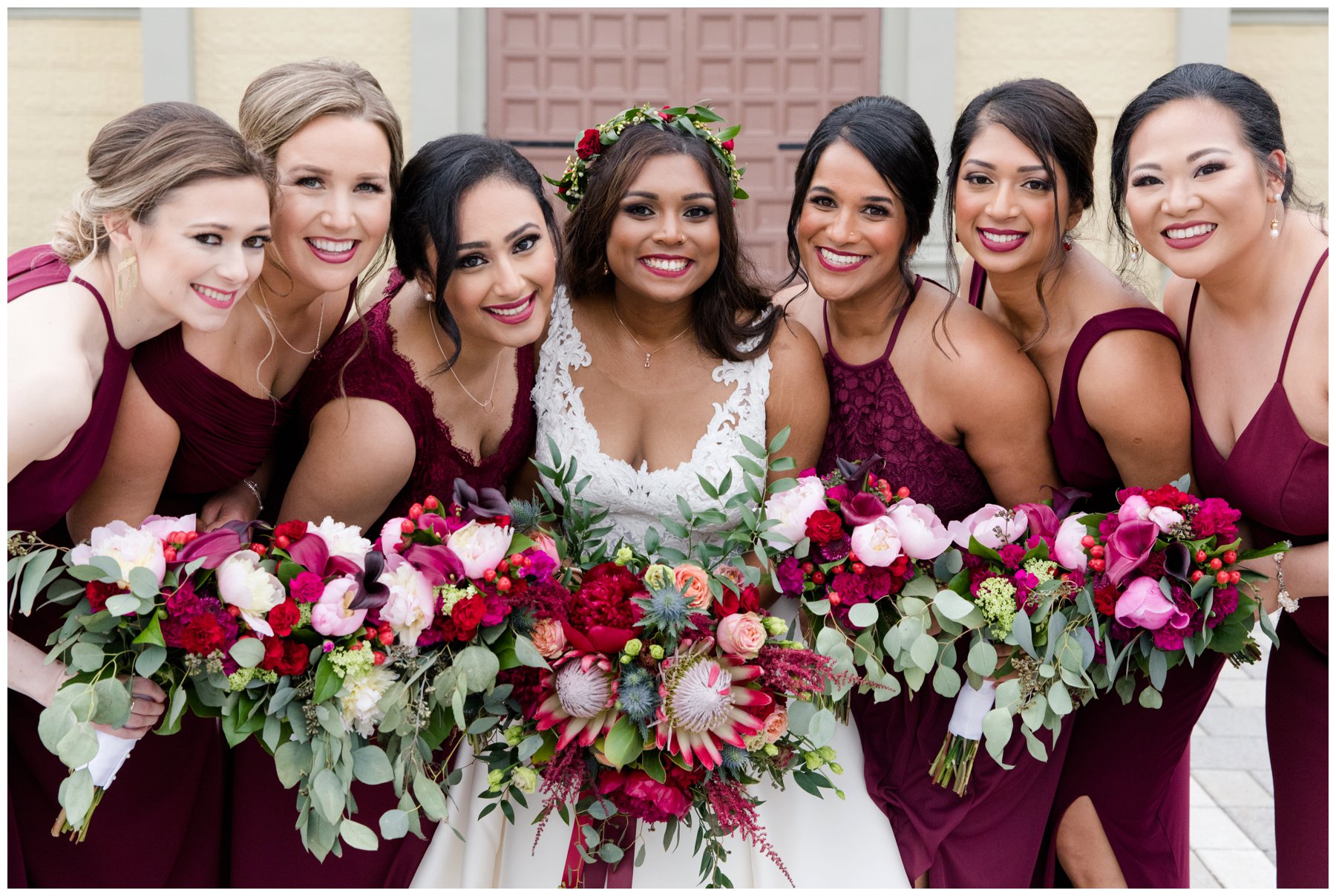 Burgundy bridesmaids with red protea and red peonies